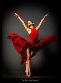 beautiful ballerina posing in a red dress in an emotive dance pose